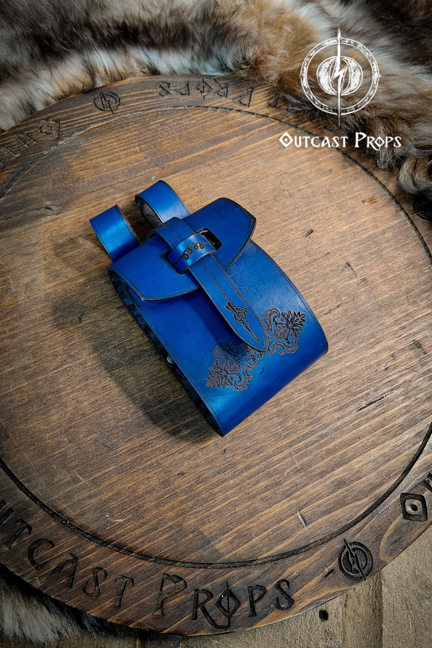 Blue leather pouch on a wooden surface with 'Outcast Props' branding. Leather Vial Case for 3 plastic vials. Adventurers, steampunk, alchemist, healers, cosplay or just to keep spices