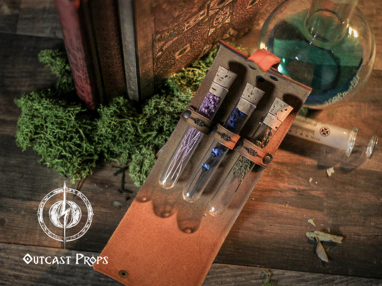 Set of small bottles with colorful liquids in a leather case on a wooden surface with greenery and a glass container.