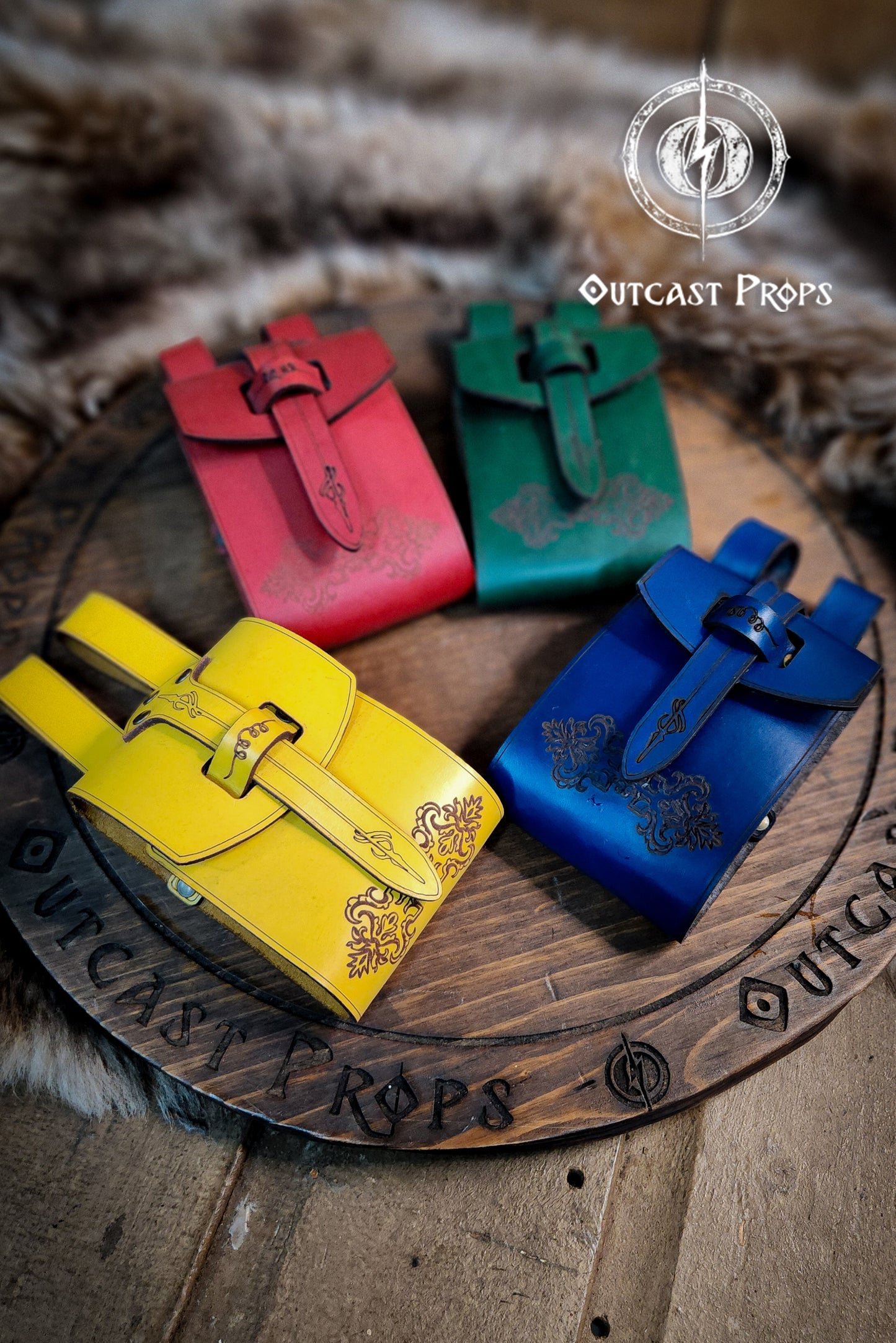 Four colorful leather bags on a wooden surface with 'Outcast Props' branding. Leather Vial Case for 3 plastic vials. Adventurers, steampunk, alchemist, healers, cosplay or just to keep spices
