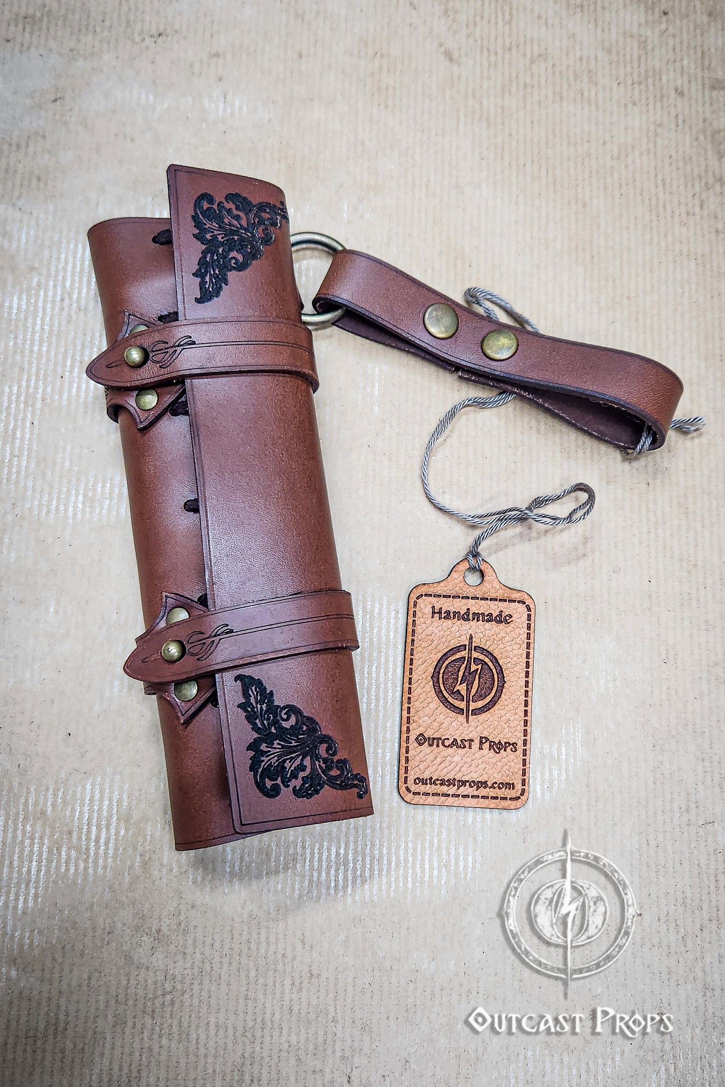 Brown leather roll with decorative elements and a matching keychain on a beige background, featuring 'Outcast Props' branding. 6 Small Potion leather case, vertical belt kit for LARP, Cosplay and Costume. Easily Carry six strong cristal bottle with cork