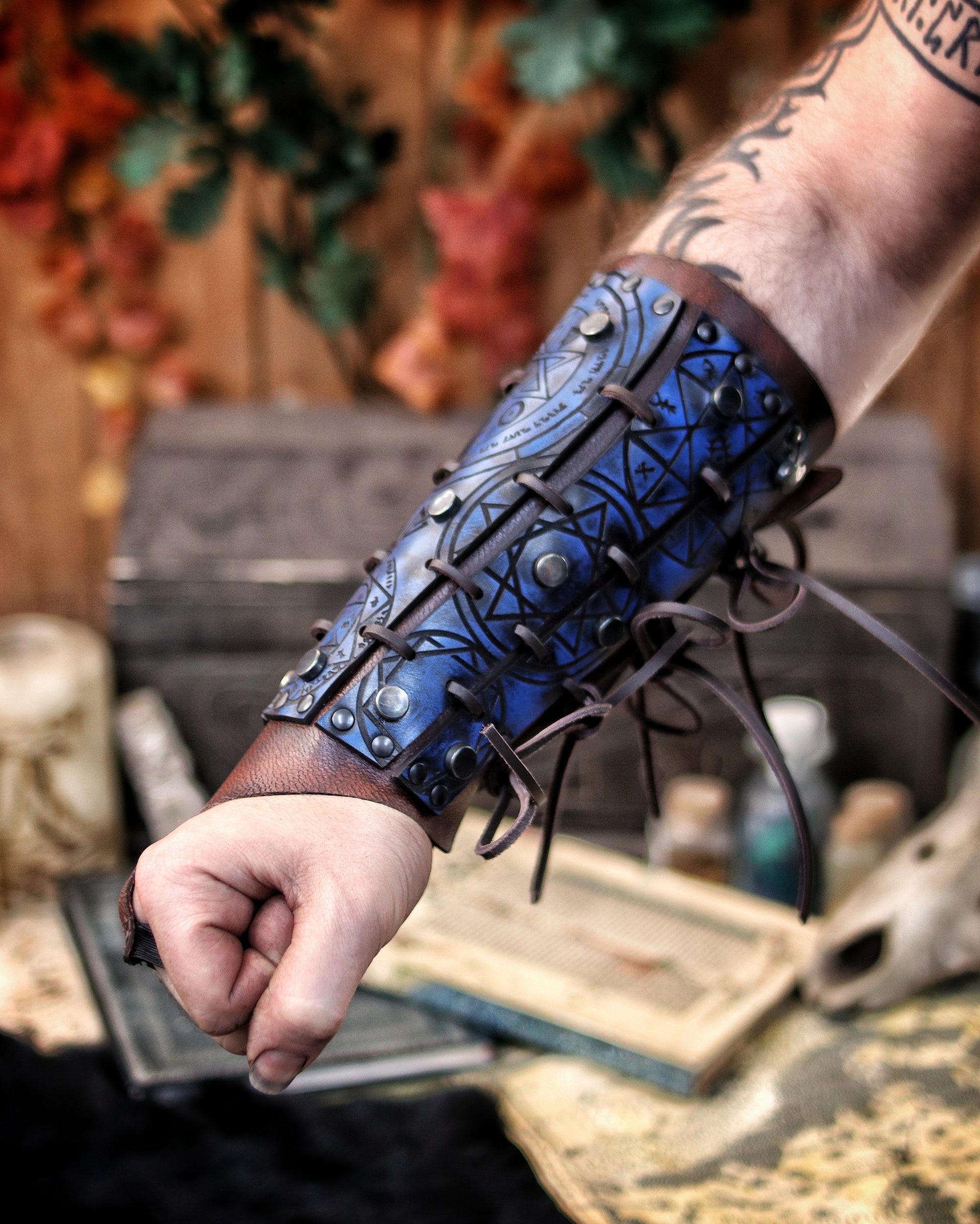 Blue leather bracer for LARP and fantasy cosplay, engraved with alchemical symbols and mystical geometry. Decorated with metal studs and polished beads for a gothic warlock or dark wizard look. Handmade from vegetable-tanned Spanish leather, adjustable and resistant. Perfect for witches, ritualists, or demon hunters in immersive fantasy roleplay.