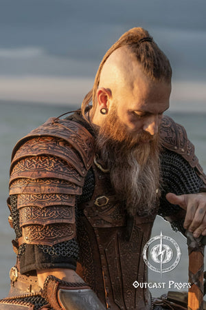 Side profile of a mohawk-bearded LARP fighter wearing Sedrik viking leather shoulder armor with engraved Celtic knots, photographed at golden hour. The layered accordion-style pauldrons provide flexibility and cinematic aesthetics. Perfect for viking cosplay shoulder armor, Nordic LARP leather pauldrons, celtic warrior costume or medieval fantasy shoulder armor for immersive events and photoshoots.