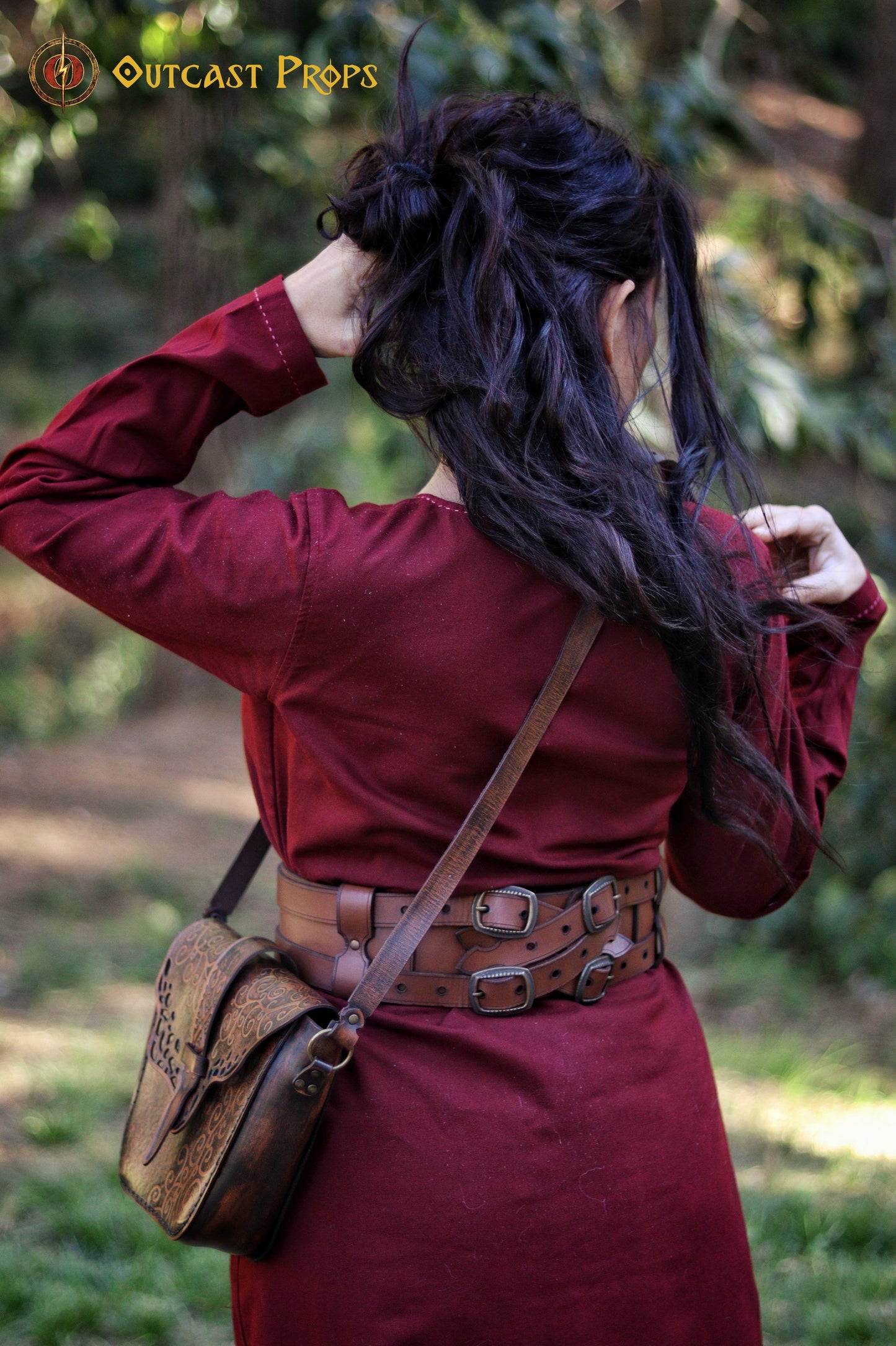 Rear view of the Adventurer Leather Belt for medieval LARP and cosplay, worn by a female model with long dark hair. The pirate-style belt wraps around her waist, holding a beautifully engraved leather pouch. This wide leather belt is fully adjustable and perfect for fantasy reenactments, offering space to attach potions, bags, and other role-playing essentials with quick access during battle scenes.