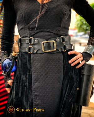 Close-up of the wide black leather belt for LARP and fantasy costumes, worn over a quilted dark dress. This unisex adventurer belt is ideal for carrying potion vials, bags, and tools during cosplay or live-action roleplay. The rugged, handcrafted buckles and reinforced design ensure both comfort and durability, making this pirate or alchemist belt a must-have for immersive adventures.