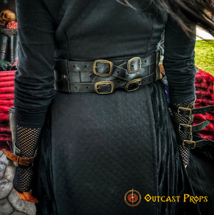 Close-up of the Adventurer Leather Belt in black, worn over a dark quilted dress with fantasy gauntlets. This wide leather belt for LARP, cosplay, and steampunk costumes features four brass buckles and reinforced stitching. Perfect for female and male characters in medieval or pirate settings, it provides adjustable support and attachment points for accessories, offering both functionality and immersive style.