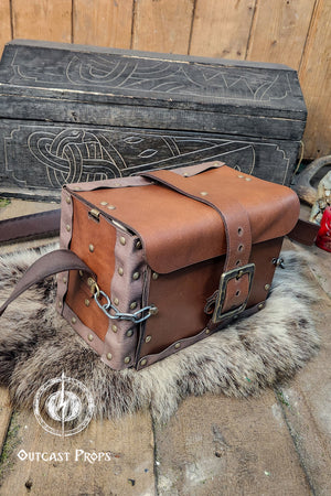 Alchemist leather larp Bag Potion Set for steampunk, alchemist costume, mage, witch, chef, healer or assassin cosplay. Natural Leather Bag. Brown leather bag with metal clasps on a fur surface, with a wooden chest in the background.