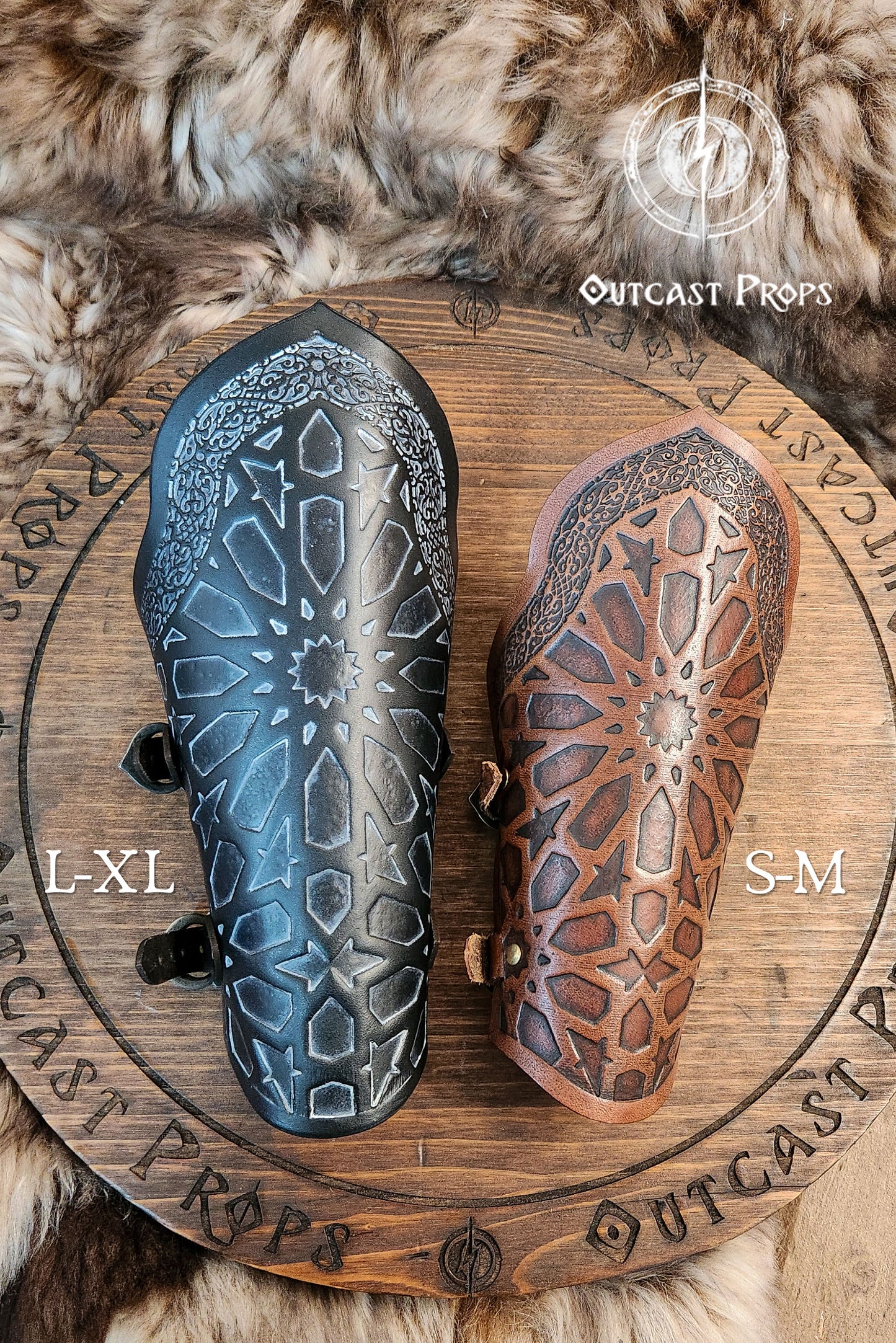 Side-by-side comparison of two engraved leather bracers showing size options: brown for S-M and black for L-XL. Both feature the same intricate Arabic pattern and are placed on a wood and fur background with the Outcast Props logo. Ideal for LARP bracers, assassin leather bracers, and oriental cosplay gear, these bracers offer adjustable comfort for different forearm sizes. This visual aids in size selection while showcasing the quality of fantasy rogue armor craftsmanship.