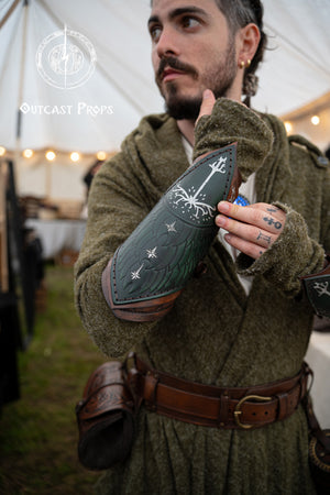 Fantasy LARP costume detail showing green Gondor vambrace engraved with White Tree, worn by an elven ranger. Embossed leather inspired by Aragorn and LOTR aesthetics. Adjustable and handmade, this bracer suits cosplay, Tolkien events, and medieval warriors. Ideal for portraying Gondorian soldiers or Middle-earth scouts. Evokes characters like Boromir, Faramir, and Númenórean descendants.