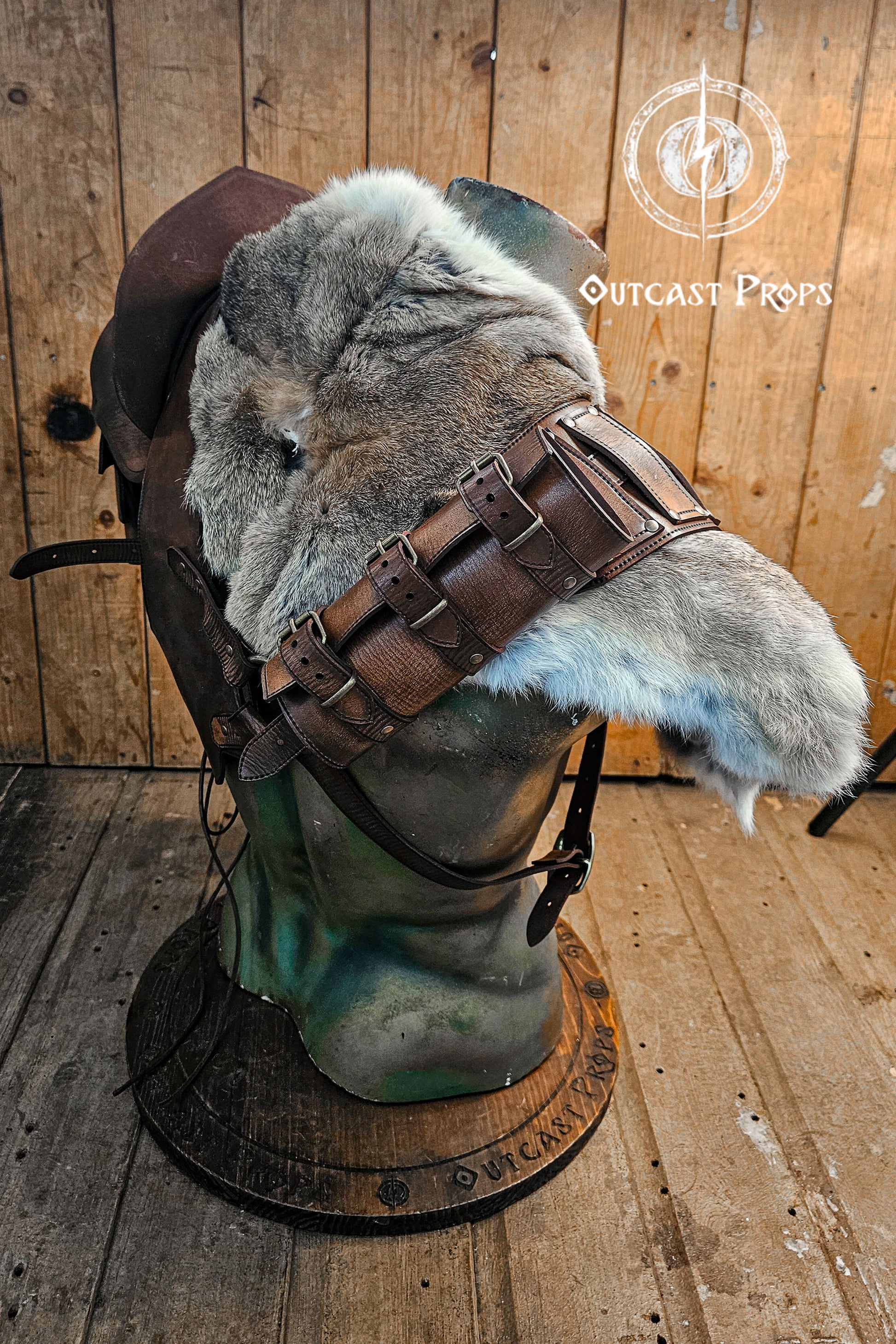 Side view of the barbarian leather armor showing the shoulder section padded with thick grey rabbit fur. A series of dark brown leather straps with aged buckles secure the fur onto the shoulder harness. Perfect for Viking cosplay, medieval warriors or LARP costumes. The fur piece adds wild realism and can be detached for modular costume customization. Artisan-crafted from full grain leather.
