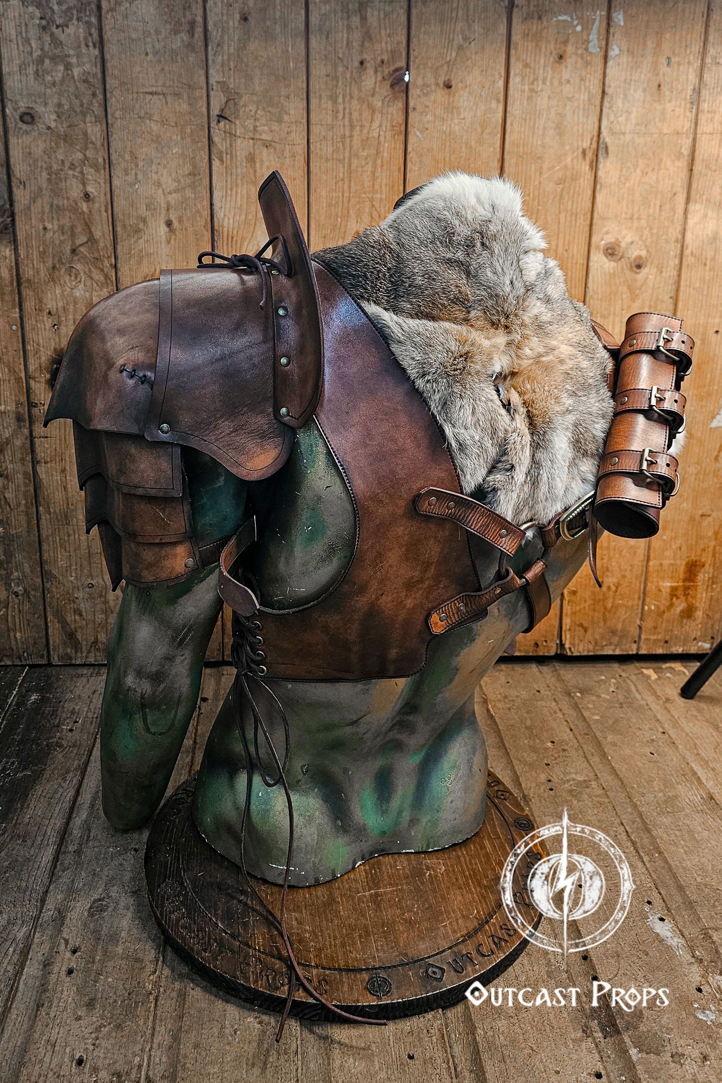 Back and side view of the barbarian shoulder armor set, highlighting the modular layering: leather harness, fur mantle, scroll holder and articulated pauldron. Brown leather straps criss-cross the torso, connecting all components with adjustable buckles. Perfect for LARP, cosplay, or Viking characters. The rugged hand-dyed leather contrasts with the soft grey rabbit fur for striking visual depth.
