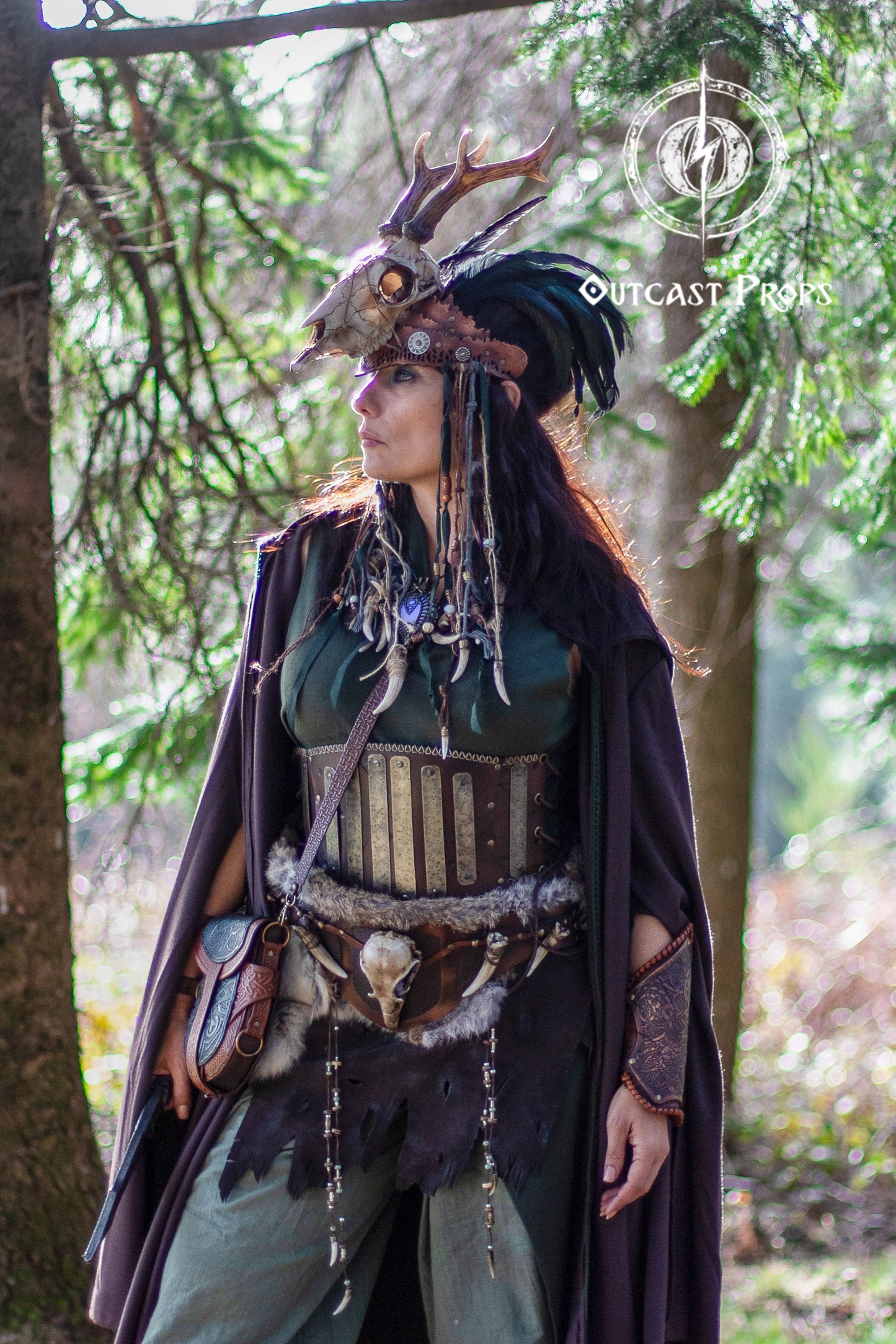 Person in elaborate costume with antler headpiece in a forest setting. Barbarian Leather armor woman, larp armor woman viking piece woman post apocalyptic cosplay
