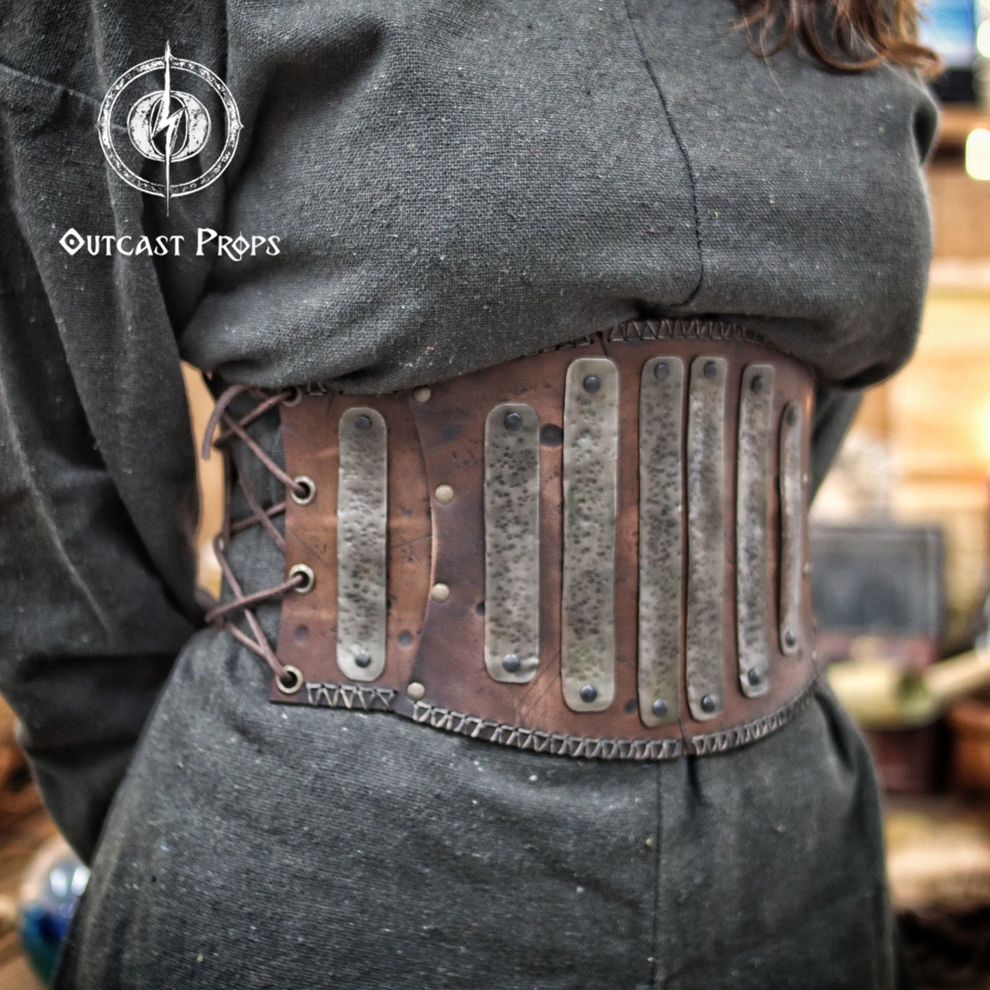 Barbarian Leather armor woman, larp armor woman viking piece woman post apocalyptic cosplay. Person wearing a steampunk-style belt with metal plates and leather straps, branded 'Outcast Props'.