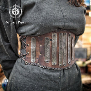 Barbarian Leather armor woman, larp armor woman viking piece woman post apocalyptic cosplay. Person wearing a steampunk-style belt with metal plates and leather straps, branded 'Outcast Props'.