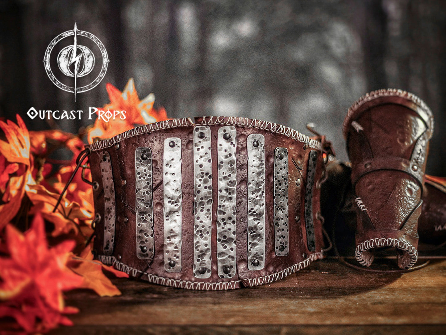 Decorative leather belt with metallic accents on a wooden surface, featuring 'Outcast Props' logo. Barbarian Leather armor woman, larp armor woman viking piece woman post apocalyptic cosplay