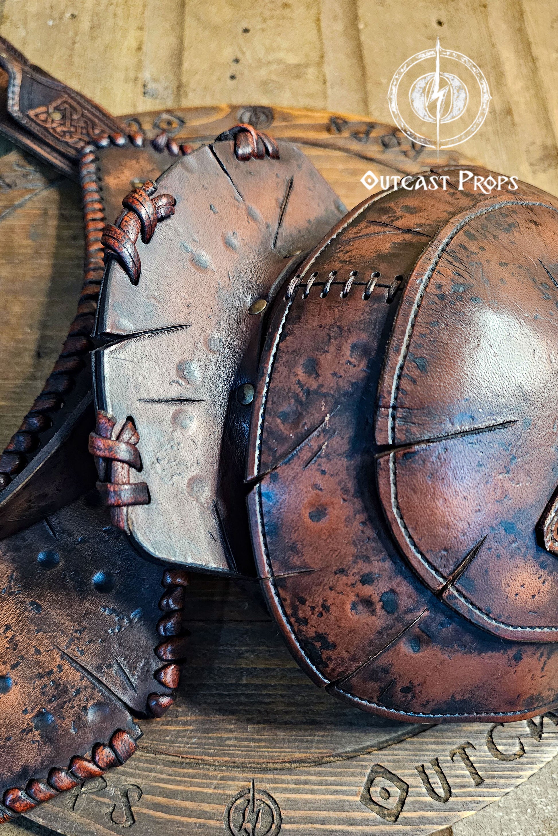 Barbarian Viking Leather Shoulder armor set. Close-up of leather armor pieces with 'Outcast Props' branding on a wooden background.
