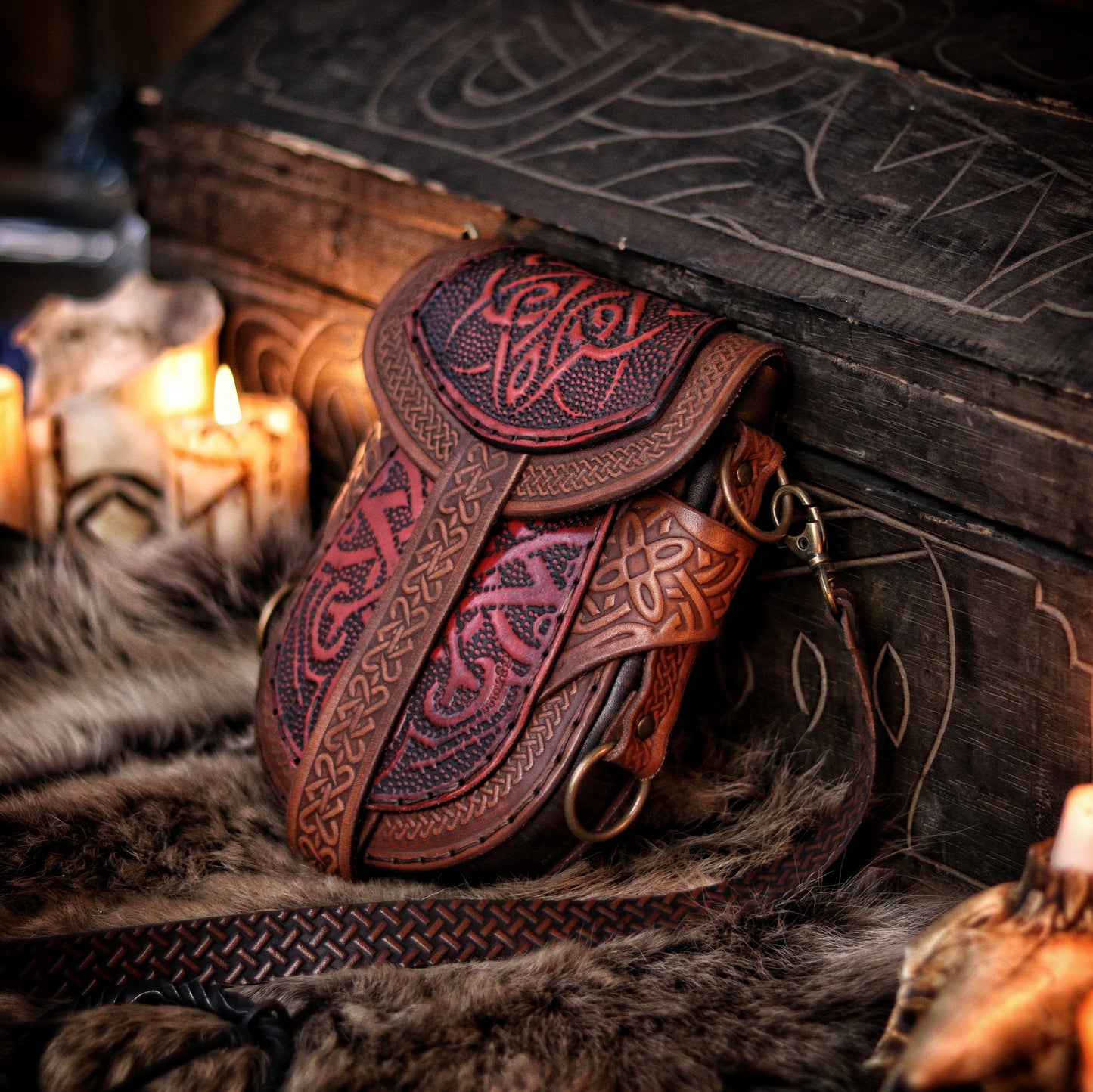 Red and brown Celtic pouch with hand-embossed leather, placed against rustic wood and soft fur. The intricate knotwork and flame-like embossing evoke fantasy and ancient warrior aesthetics. Ideal for LARP costumes, renaissance fair outfits, or as a daily medieval accessory. Handcrafted in Spain using sustainable materials, with dual carrying options. Perfect blend of beauty and function.