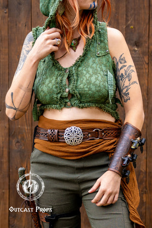 Person wearing a green top and brown skirt with tattoos and accessories against a wooden background. Celtic knot leather belt silver buckle larp belt for ren fair fantasy costume celtic belt unisex leather belt for renaissance outfit