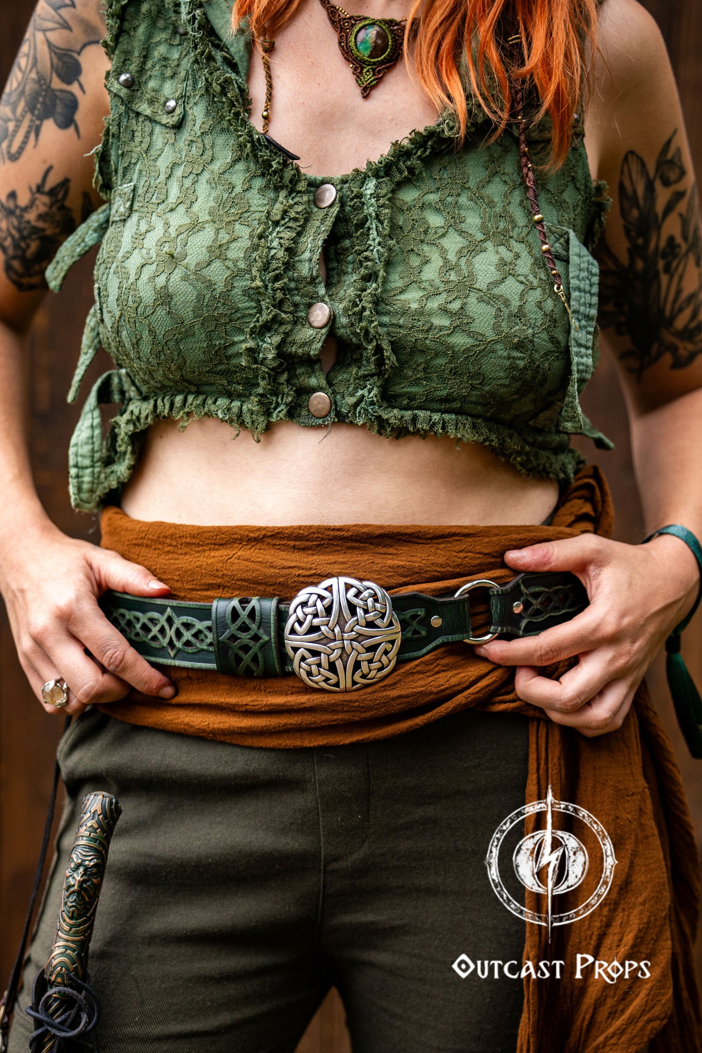 Person wearing a green lace top and brown pants with a belt, holding a sword, against a dark background. Celtic knot leather belt silver buckle larp belt for ren fair fantasy costume celtic belt unisex leather belt for renaissance outfit