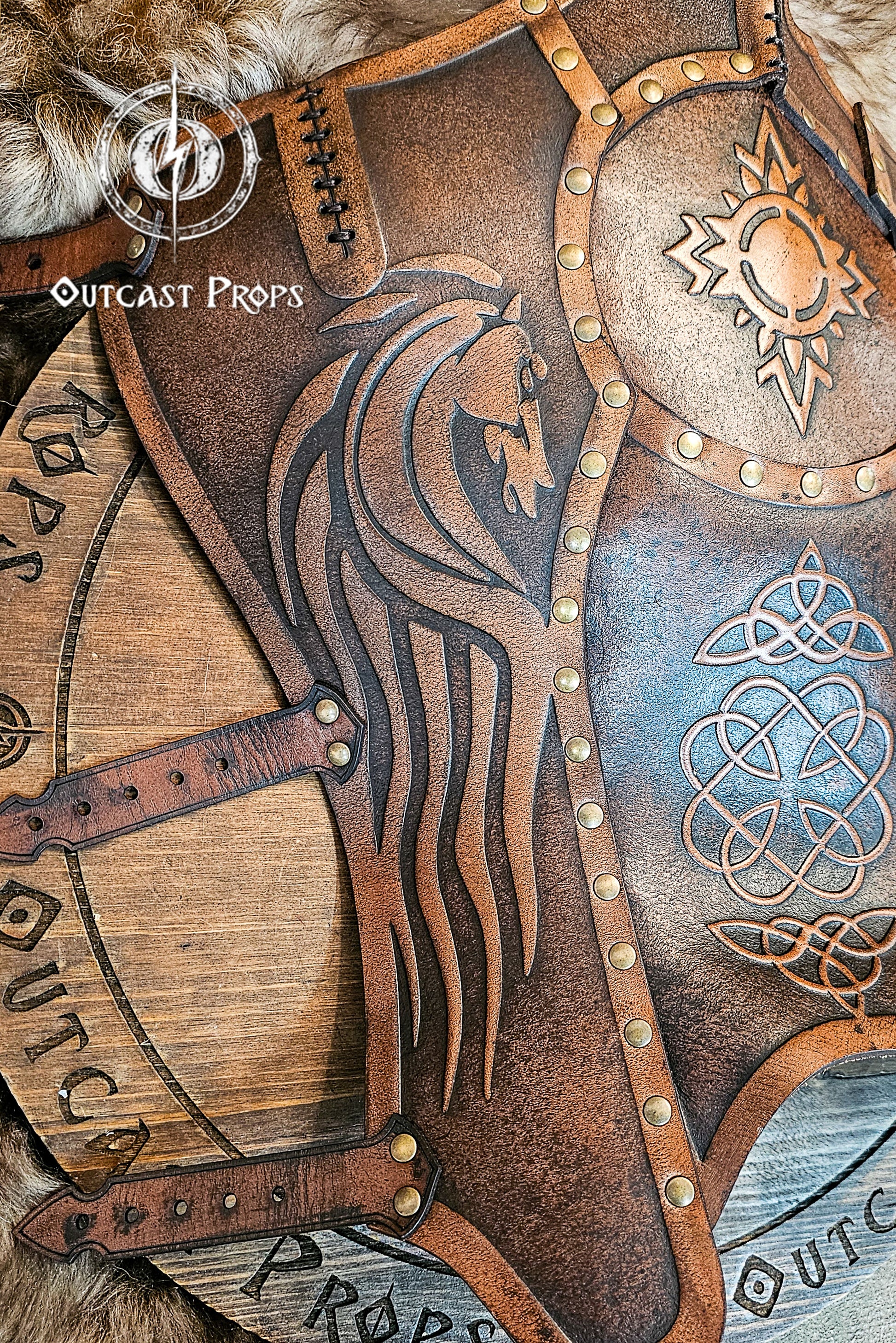 Macro detail of a Celtic leather greave showing the embossed horse’s head and intricate knot patterns symbolizing courage and lineage. Each curve, rivet, and burnished edge reflects Outcast Props’ handcrafted precision. Made from vegetable-tanned leather, aged and dyed for LARP and medieval reenactments. Ideal for Rohirrim horsemen, Viking warriors, and fantasy riders seeking authentic leather leg armor.