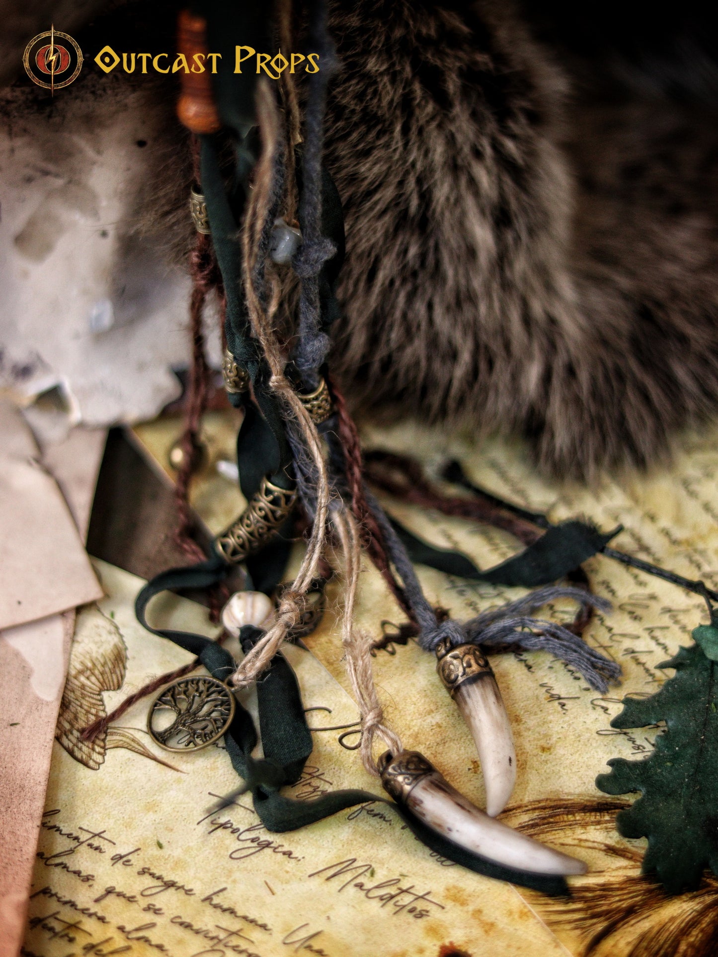 A Celtic adorned tiara with a resin skull, deer horns, feathers, bone pieces, beads, and fangs displayed on a table with a wooden background and candles. Beltane Headpiece tribal deer horns skull and feathers tiara leather and resin