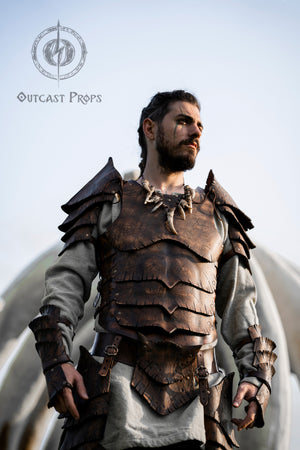 Front close-up of a man wearing the Dragon Scales Armor Set, staring into the distance with war paint under his eye. The armor’s layered leather plates, engraved and aged to look like dragon scales, evoke strength and legend. Ideal for LARP, medieval fantasy cosplay or Ren Faire, this set features handmade craftsmanship with a cinematic finish that enhances barbarian, cursed knight, or dragon hunter characters.