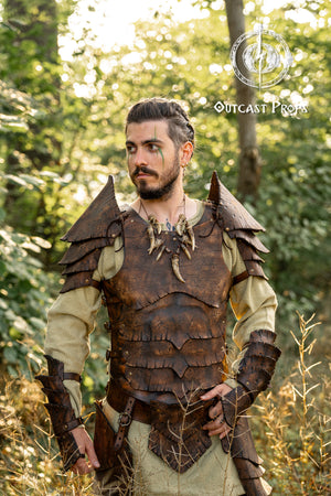 Fantasy warrior wearing full brown leather armor set inspired by dragon scales, with layered pauldrons, vambraces, and chestplate. Captured outdoors in a sunlit forest, ideal for portraying a ranger, druid, or wild elf character in LARP or fantasy cosplay. The handcrafted leather is aged and painted for a cinematic finish. Natural surroundings enhance the immersive look of the armor, designed for heroic roleplay and medieval adventures.