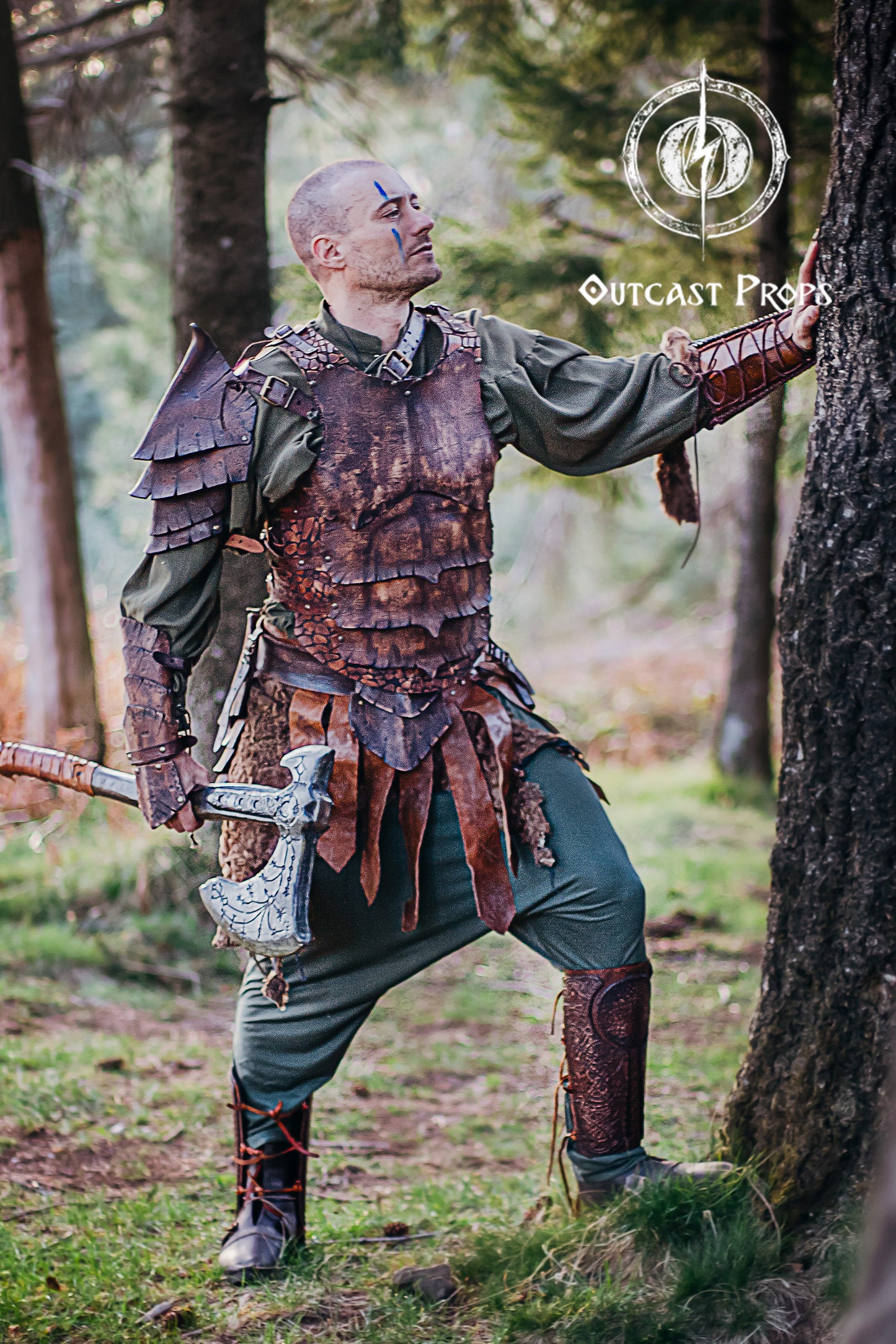 Full body shot of a LARP warrior in brown dragon scale armor, standing in the forest holding a fantasy axe. The leather bracer features rugged scale patterns and is perfect for orc characters, monster slayers or forest rangers. Handmade from high-quality vegetable-tanned leather and uniquely aged by hand. This cosplay bracer is built for epic campaigns and immersive roleplay.