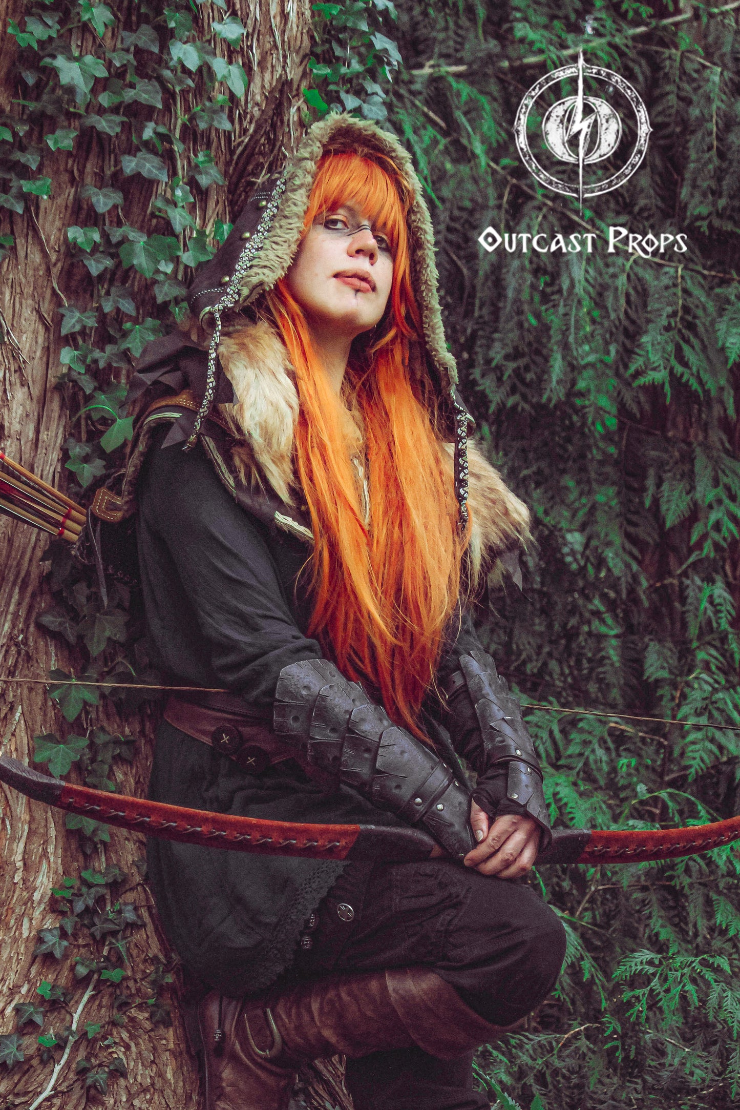 Female archer character with long orange hair and fur-trimmed hood leans against a tree, wearing black dragon scale bracers. The bracers add fierce elegance to LARP costumes, fantasy elf cosplay or rogue outfits. Made from genuine leather and aged by hand, these vambraces offer both comfort and bold style for medieval fairs or immersive fantasy adventures.