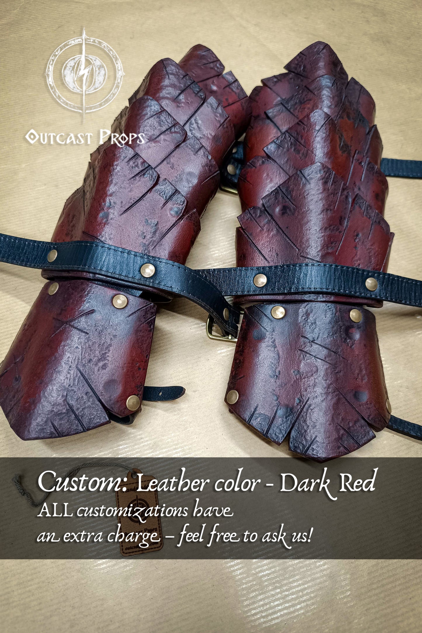 Pair of dark red leather dragon scales armor gauntlets with black straps on a beige background, featuring Outcast Props branding.
