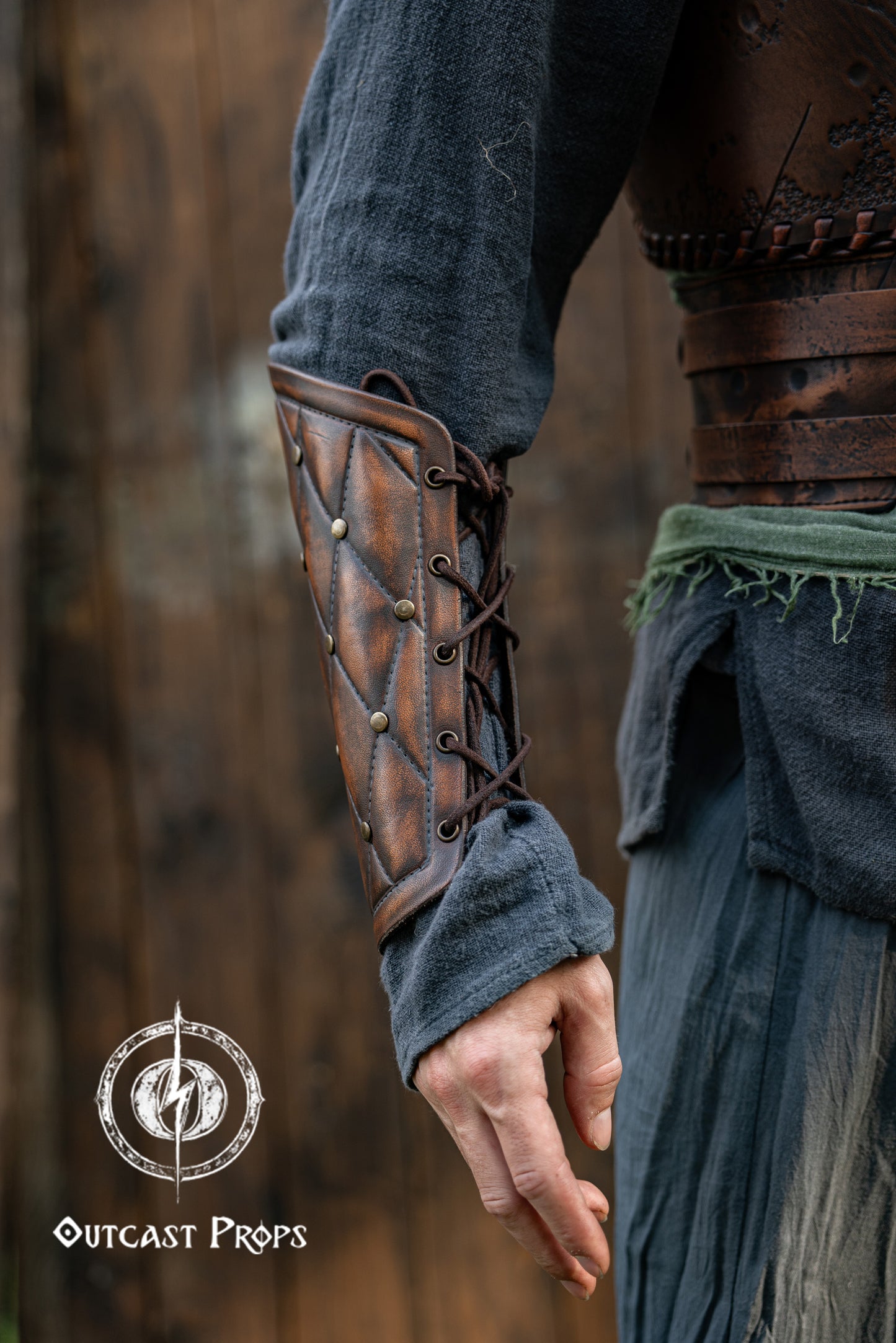 Close-up of a person wearing a leather arm guard with a blurred background. Falken leather bracers for noble costume LARP outfit medieval fantasy accessories for Ren Faire cosplay arm guards for knight character gear