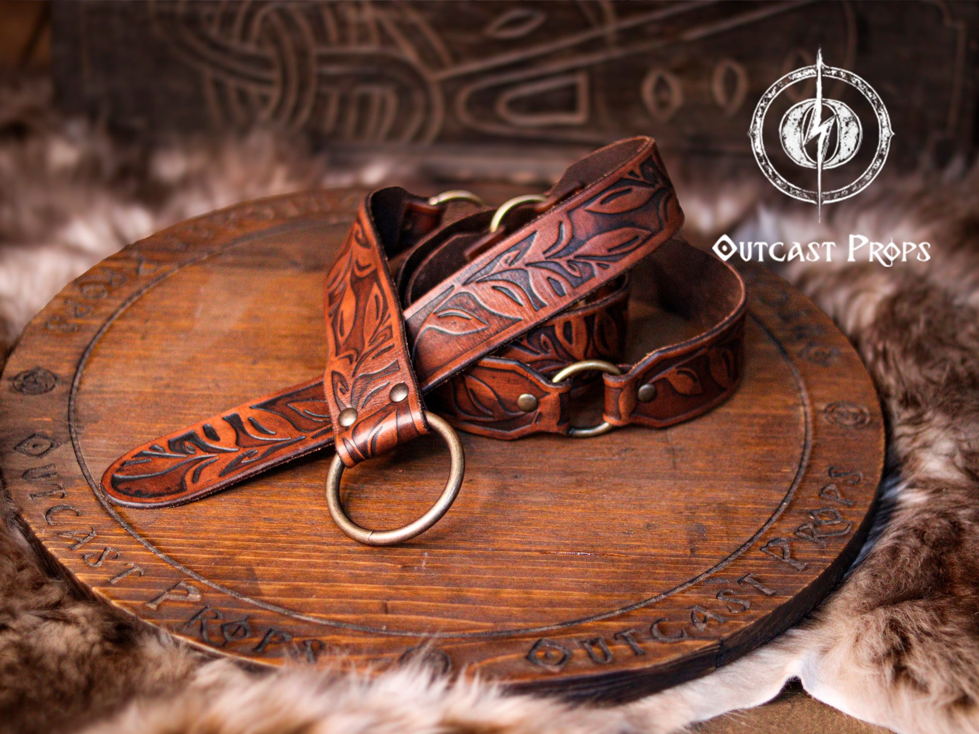 A handcrafted Floral Leather Belt with O-Rings in rich brown tones, curled elegantly atop a rustic carved wooden board. This Renaissance Leather Belt with O Rings Fantasy Elven Waist Belt is tooled by hand with intricate leaf designs, ideal for medieval cosplay, LARP outfits, and fantasy fairs. Made with premium vegetable-tanned leather, showcasing artisanal craftsmanship and durable beauty.
