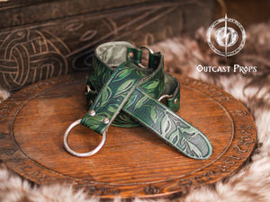 Close-up of a green Floral Leather Belt with O-Rings rolled on a rustic fur and wood background. Perfect for Fantasy Elven LARP Belt and Ren Faire Medieval Cosplay Waist Belt outfits, this piece is hand-tooled with leaf patterns on premium vegetable-tanned leather. Ideal for adding a vibrant fantasy touch to LARP costumes, medieval festivals, or elven cosplay gear with authentic handmade charm.