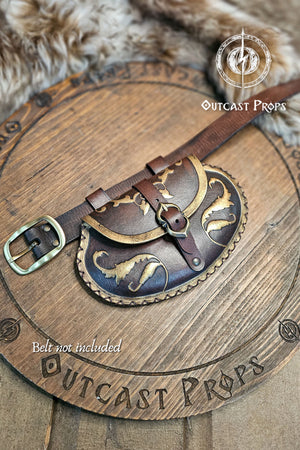 Aged brown renaissance leather belt bag lying flat on engraved wooden board. The small pear shaped pouch shows elegant gold ornaments on flap and edges, with a central brass buckle closure. Two leather loops attach it to a belt. Perfect for LARP, cosplay or renaissance fair noble outfits, this handmade vegetable tanned leather pouch blends style and practicality.