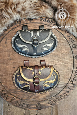 Two renaissance leather pouches displayed together, one in black with silver ornaments and the other in brown with gold details. Both have pear shapes and belt loops for attachment. Perfect noble accessories for LARP, fantasy or renaissance fair costumes, handmade from eco-friendly vegetable-tanned leather using Outcast Props’ artisanal aging process.