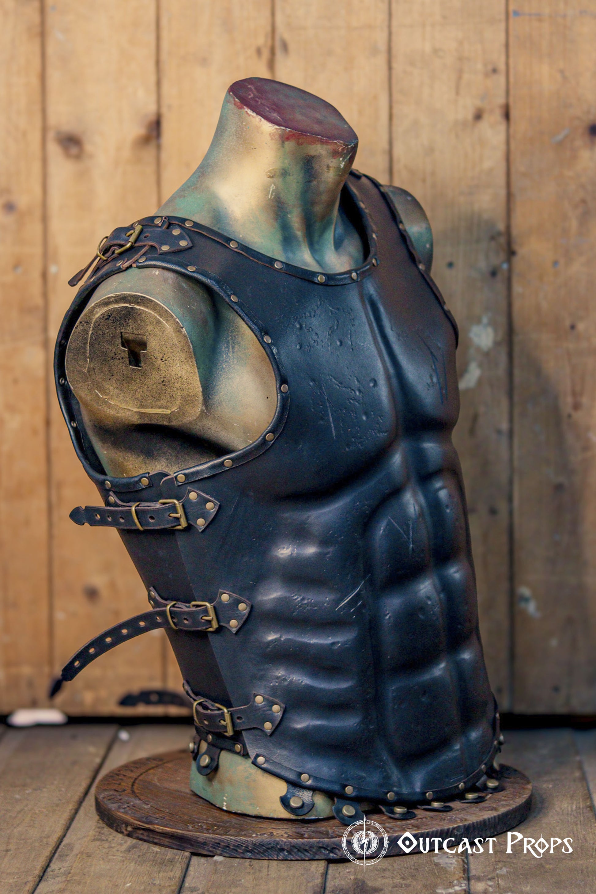 Side view of black leather Roman musculata cuirass with antique brass buckles and reinforced rivets, designed for LARP, Roman cosplay, or fantasy warriors. The sculpted abs and historical fit evoke the classical Greek ideal. Leather textures and shaped contours make the armor accessible to visually impaired users by enhancing tactile detail. Handmade and dyed with eco-friendly methods.