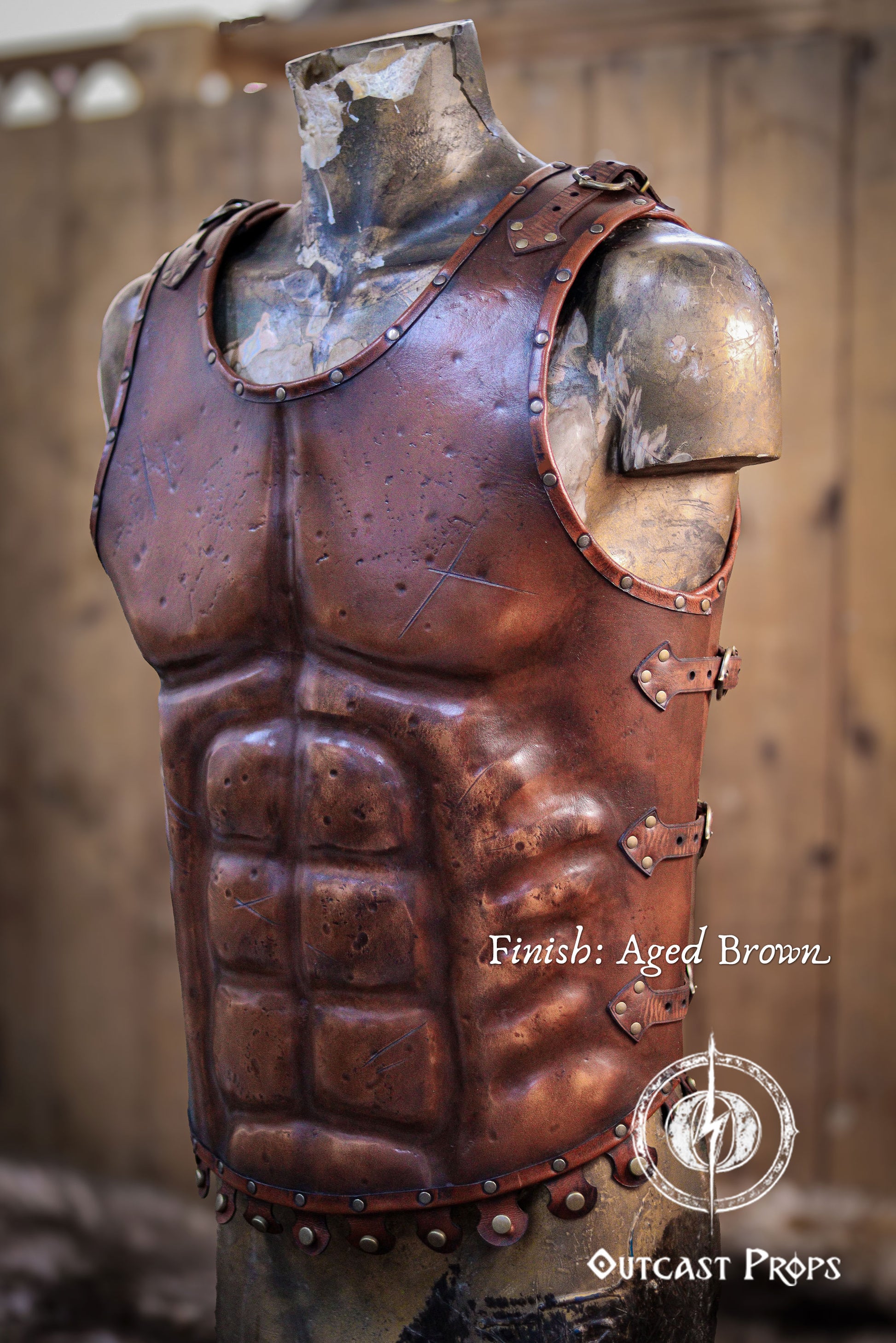 Close-up video of the leather Roman gladiator armor, displaying detailed muscle shaping and battle scratches. This musculata cuirass is ideal for LARP events, cosplay warriors, and reenactment fans. Made with vegetable-tanned leather and hand-riveted accents, it mimics the heroic physique of Roman generals and fantasy heroes with striking realism. Aged brown leather armor on a mannequin with 'Outcast Props' branding.