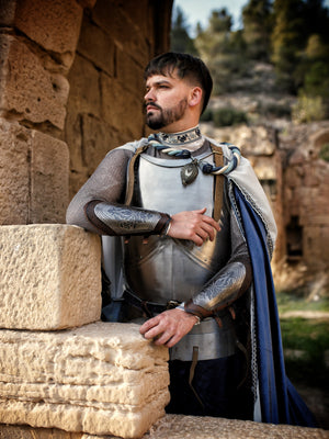 Close-up of a medieval knight costume showing detailed engraved leather bracers with silver metal plates, floral motifs, and leather straps. Perfect for fantasy cosplay, LARP armor, or noble character outfits. The texture of the armor and natural light enhance the historical look. Ideal accessory for renaissance fair or fantasy roleplay events.