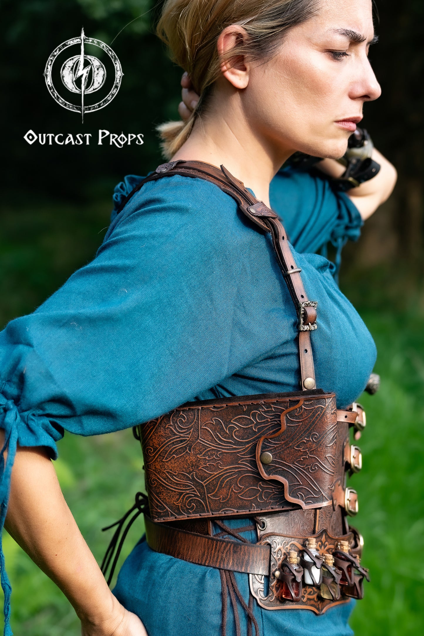 Ornated Magic Wand shoulder Holster full-grain leather with potions for wizards and witches. Dark Academy style. MACUSA Cosplay and LARP. A person wearing a white shirt and a shoulder holster in a patterned fabric. The holster is brown, made of leather, and designed to hold a wand.