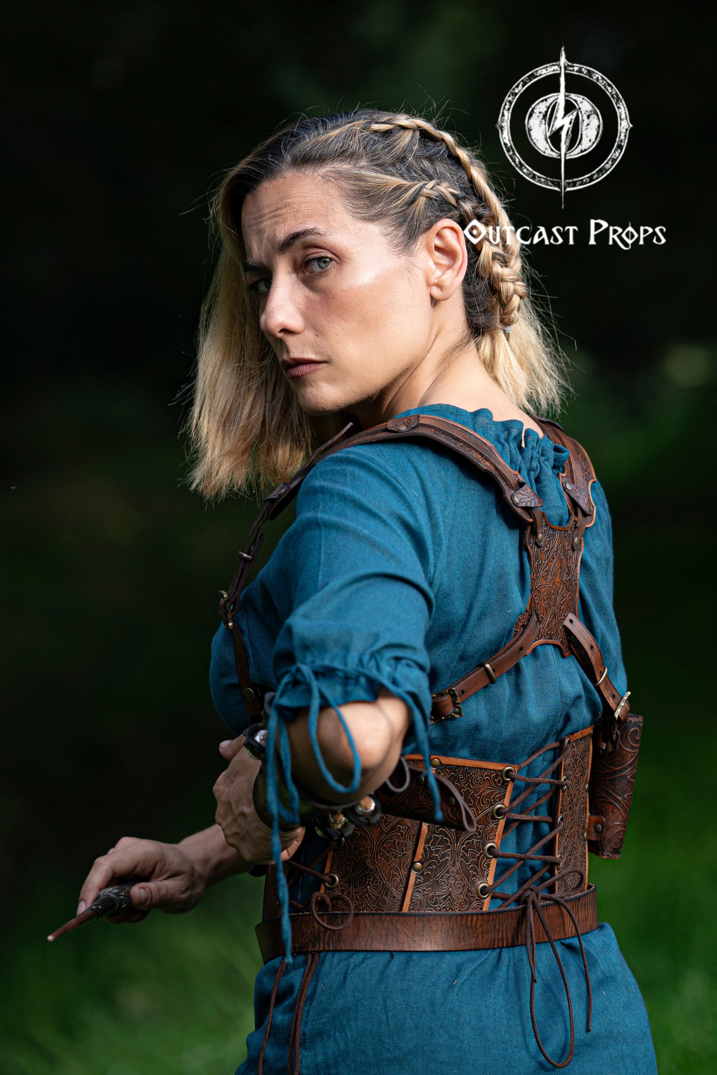 Person in medieval attire with a leather harness, holding a bow, against a dark background. Ornated Magic Wand shoulder Holster full-grain leather with potions for wizards and witches. Dark Academy style. MACUSA Cosplay and LARP. A person wearing a white shirt and a shoulder holster in a patterned fabric. The holster is brown, made of leather, and designed to hold a wand.