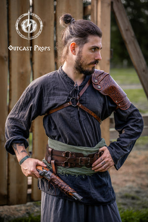 Man in Viking attire with leather armor and weapons, standing outdoors. Leather Shoulder Pauldron: Musketeer Armor for LARP, Renaissance LARP, cosplay, Ren Faire accessory, Aramis inspired