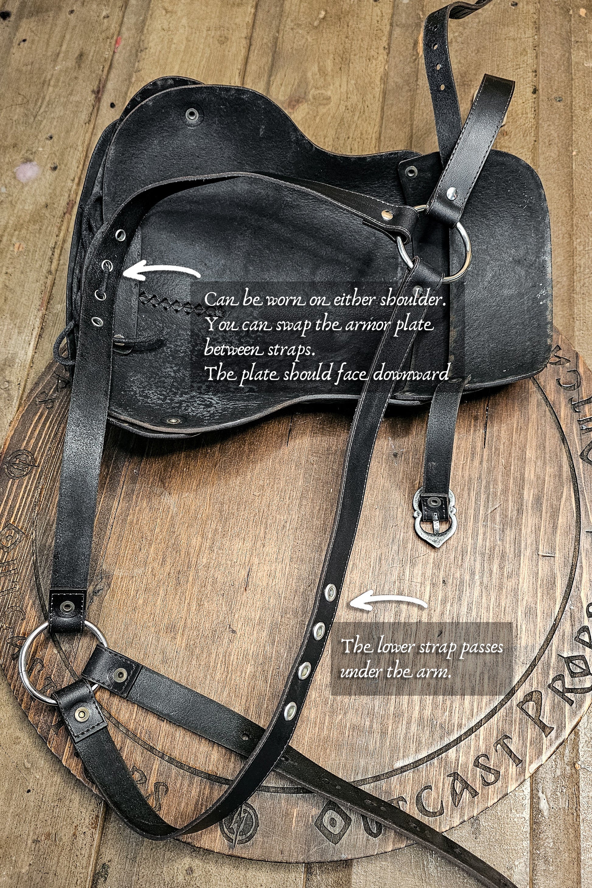 Black leather armor plate with instructions on a wooden background. Leather Shoulder Pauldron: Musketeer Armor for LARP, Renaissance LARP, cosplay, Ren Faire accessory, Aramis inspired