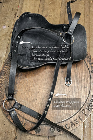Black leather armor plate with instructions on a wooden background. Leather Shoulder Pauldron: Musketeer Armor for LARP, Renaissance LARP, cosplay, Ren Faire accessory, Aramis inspired