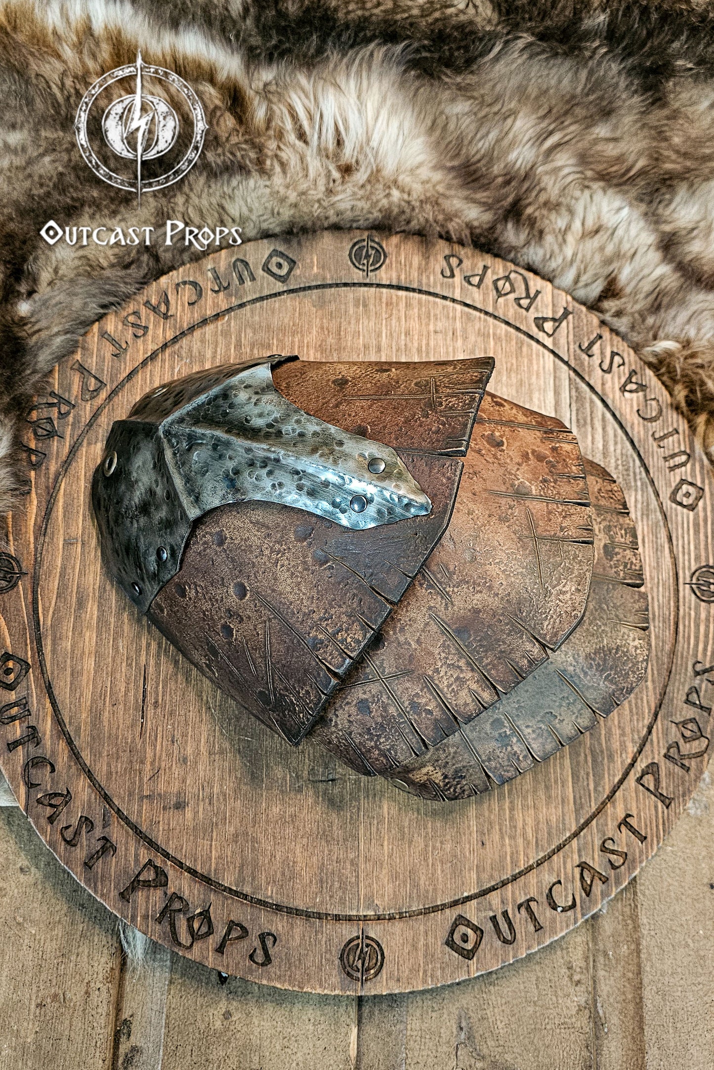 Close-up of a handcrafted leather and metal pauldron with layered aged brown plates, showing realistic texture and hammered steel. The armor combines Viking and barbarian design with orcish details, perfect for LARP or cosplay costumes. Made by Outcast Props using premium vegetable-tanned leather and unique aging techniques for a battle-worn authentic look.
