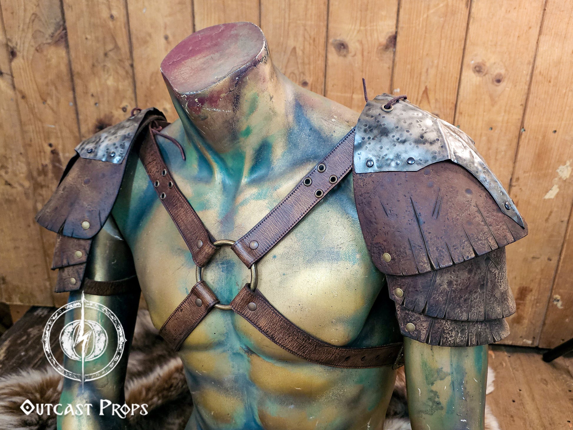Close front view of the handmade Outcast Props double pauldron armor on a torso mannequin. The crossed leather straps and hammered steel plates evoke Viking, barbarian, and ork aesthetics. Every piece is shaped, dyed, and aged by hand using eco-friendly techniques, offering authentic LARP and cosplay armor with cinematic, battle-worn detail.