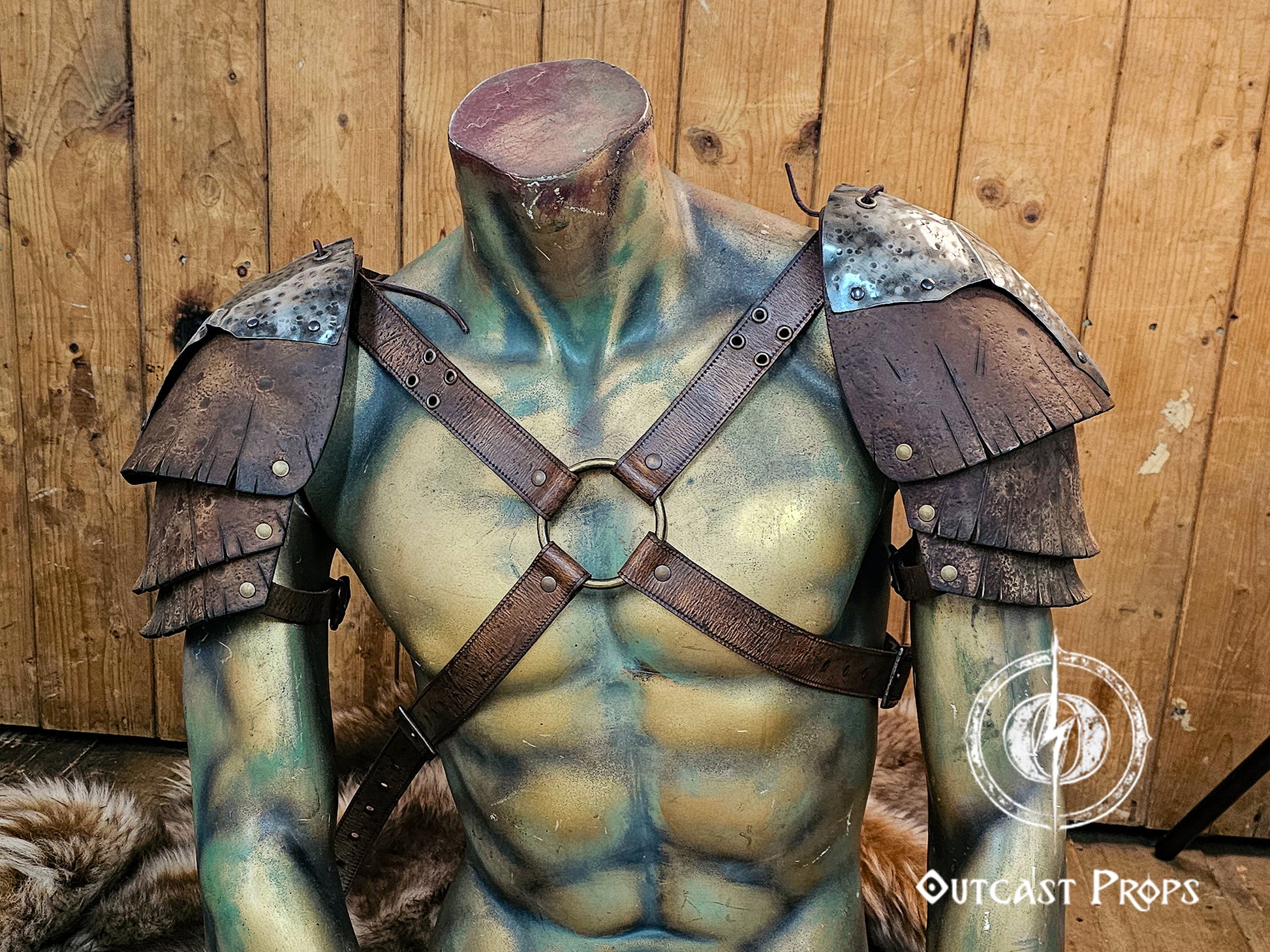 Front view of the full leather and metal pauldron set displayed on a mannequin, highlighting the chest harness structure. The brown vegetable-tanned leather shows carved and aged textures inspired by Viking and ork armor styles. Perfect for LARP, fantasy, and cosplay warriors, this handcrafted armor embodies Outcast Props’ unique aging craftsmanship.
