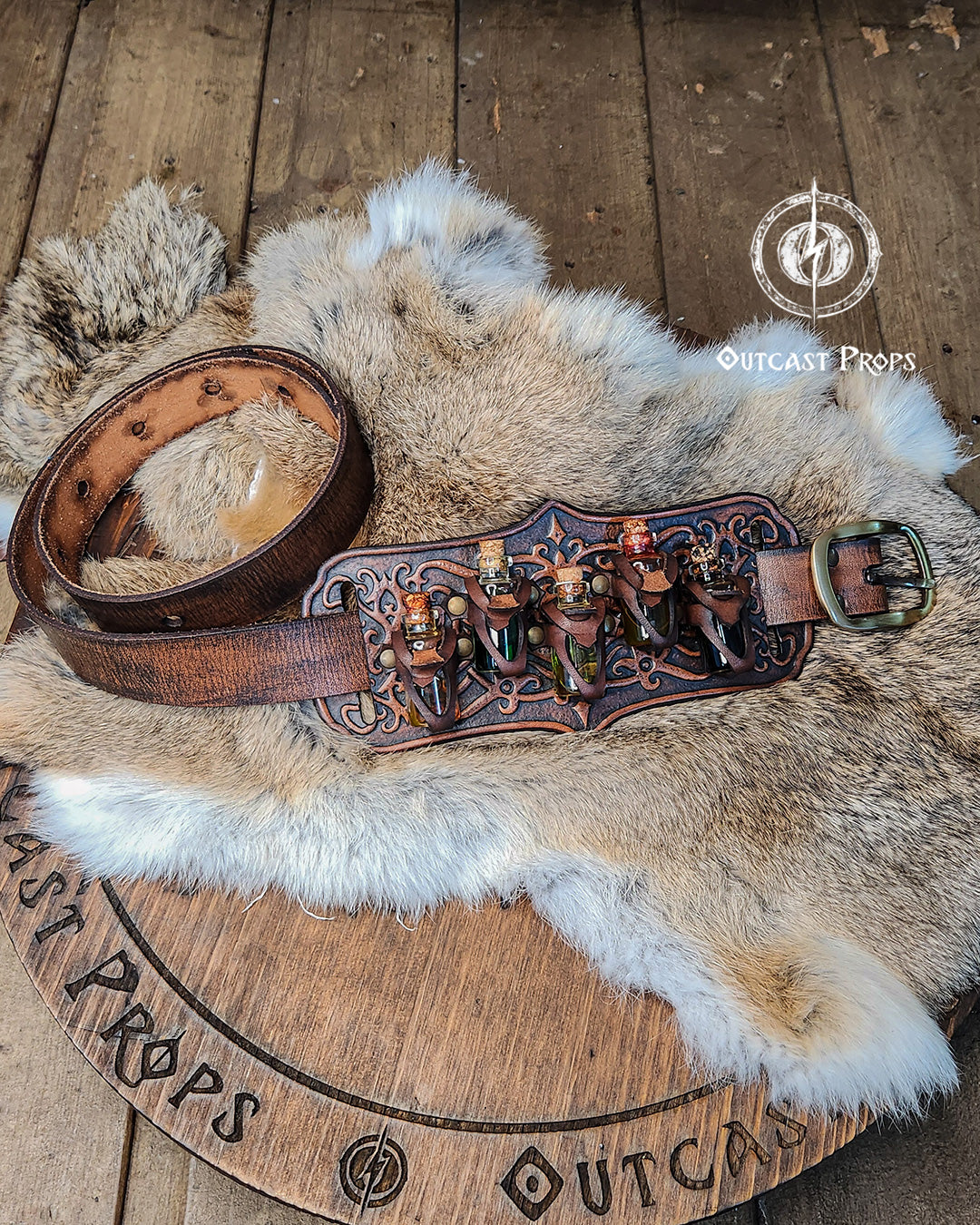 A handmade leather potion holder with ornate embossed patterns, designed to hold five small glass vials. The holder is displayed on a furry surface, and the vials have cork stoppers. Ornated Belt potion holder | 5  potion Belt carrier | LARP, cosplay, fantasy alchemist accessory, adventurers, steampunk, alchemist, healers