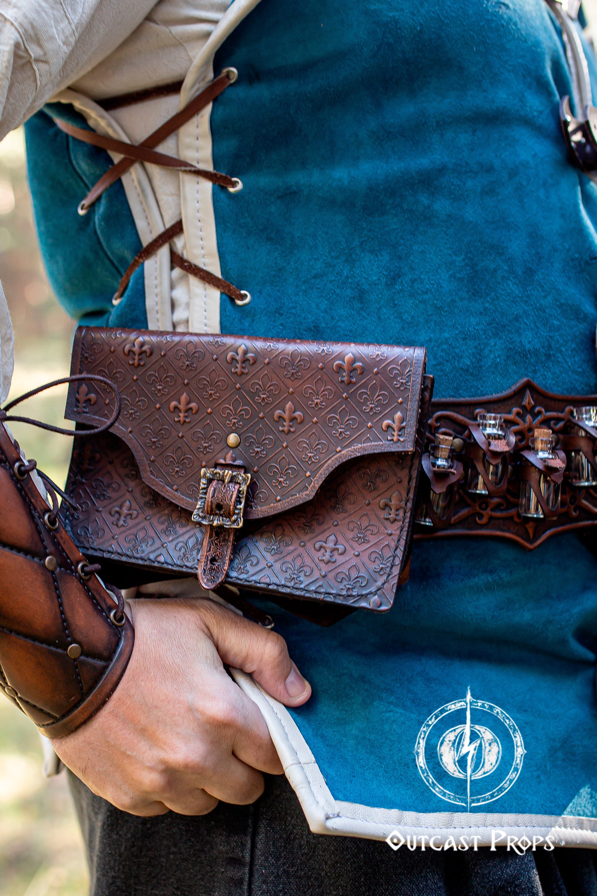 A handmade leather potion holder with ornate embossed patterns, designed to hold five small glass vials. The holder is displayed on a furry surface, and the vials have cork stoppers. Ornated Belt potion holder | 5  potion Belt carrier | LARP, cosplay, fantasy alchemist accessory, adventurers, steampunk, alchemist, healers
