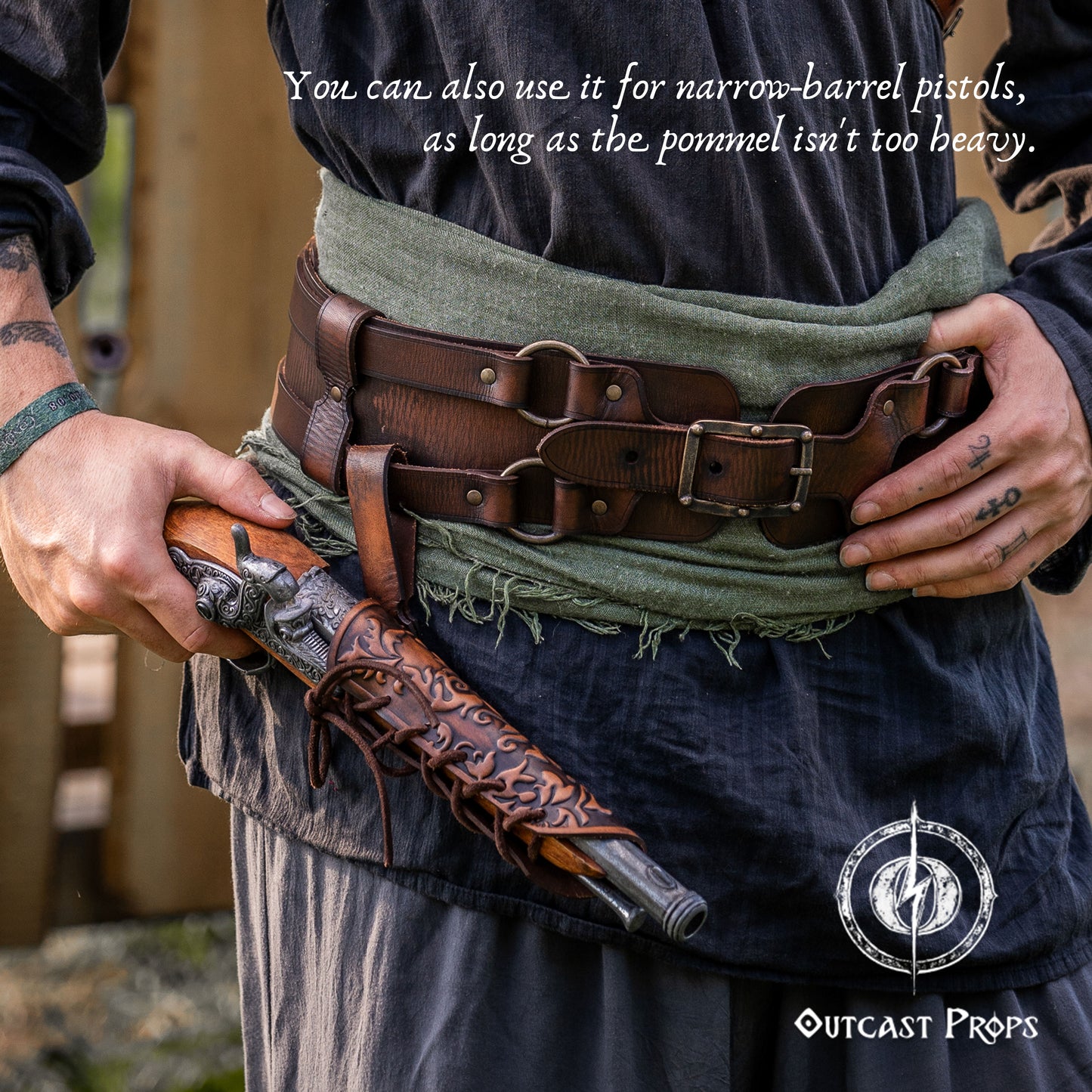 Person holding a leather-wrapped rifle with a belt and green cloth, featuring Outcast Props branding. Handmade leather dagger sheath | Ornate LARP scabbard | Viking, medieval, fantasy belt holster for daggers | Ren Faire cosplay accessory