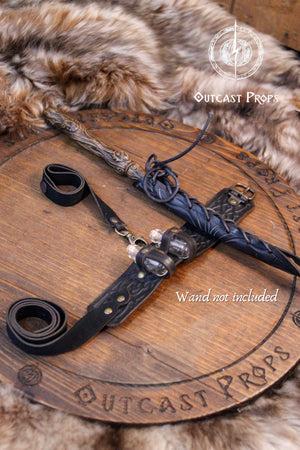 Wooden staff with leather strap on a wooden surface, Outcast Props branding visible