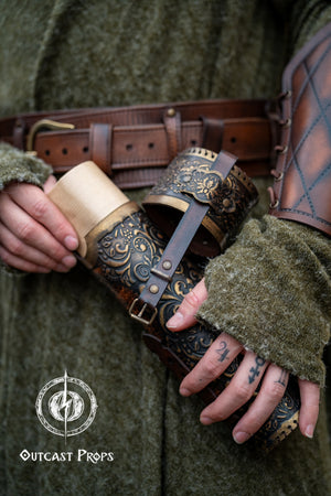 Detailed view of a fantasy scroll case being opened, revealing rolled parchment inside. The leather case is brown with golden embossed decorations, worn on the hip of a medieval-style outfit with matching bracers. Perfect LARP and Renaissance fair accessory for mages, scholars, or witches. Handcrafted with vegetable-tanned leather, perfect for storing maps, secret documents or magical scrolls.